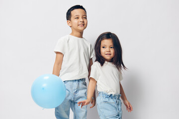 two small children a boy and a girl are standing in a white T-shirt on a light background and the boy is holding a blue balloon in his hand