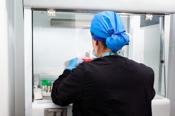 Young female scientist working in a safety laminar air flow cabinet at the laboratory