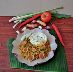 Traditional Fried Rice or Nasi Goreng with Egg Yolk and Spices on Wooden Table