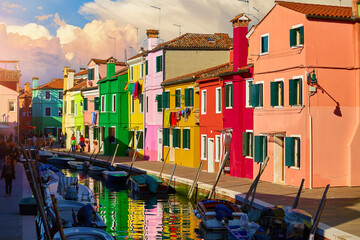 Burano island in Venice, Veneto region, Italy picturesque over canal with boats among old colourful houses stone streets.