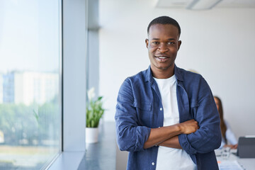 Portrait of happy young businessman standing at office. Young man standing at startup office...