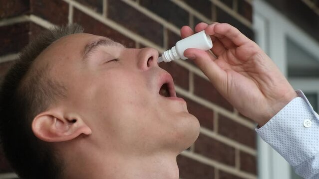 A man drips medicine into his nose, close-up