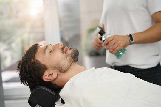 Chill brunette guy laying down in barbershop chair
