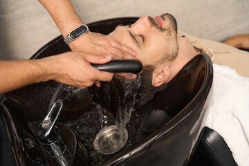 Handsome guy getting a hair wash at professional salon