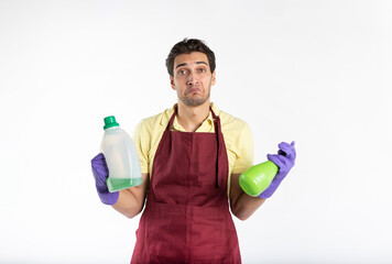 Young handsome male contractor from cleaning service wearing uniform, apron and rubber gloves holding cleaning tools and feeling bad because of exhausting household day isolated on white background