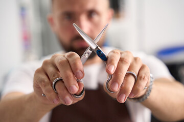Hair-grooming specialist posing with two pairs of scissors