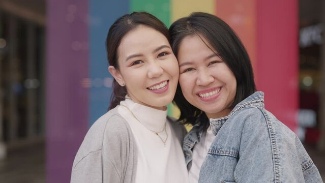 Young adult queer lover transgender asia two gay people fun happy enjoy relax look at camera. LGBT LGBTQIA beauty colorful flag color bisexual family festival hug love smile at city street town.