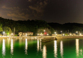 Obraz premium Quiet harbor in small coastal village under starry night sky