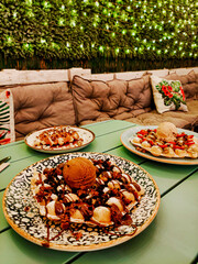 three waffle dishes with ice cream, chocolate, strawberries on a terrace with lights