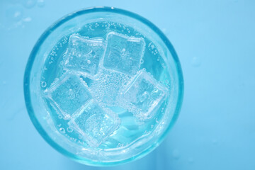 soft drinks in a glass with ice cube on blue background 