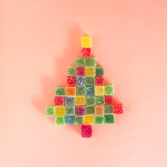 Minimal concept with colorful gummy candy like a Christmas tree. Creative New Year idea on pink...