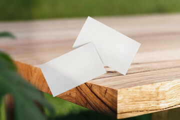 Clean minimal business card mockup floating on top wooden table and leaves