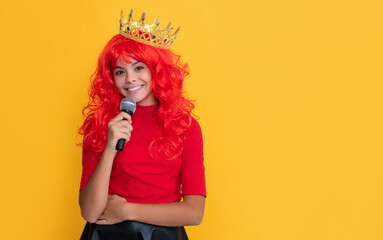 glad child in crown with microphone on yellow background
