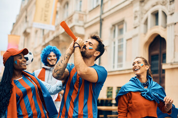 Group of cheerful sports fans celebrating after soccer match on street.