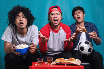 Supporter men watching football game in stress dejected and disappointed for failure shouting and...