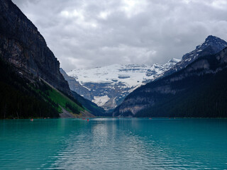 Leisure tourists in rented canoes on Lake Louise turquoise waters in Canada