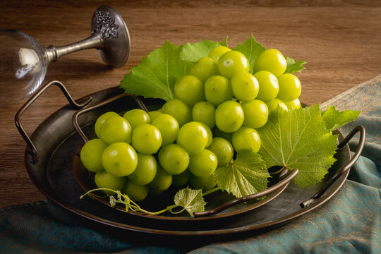 Green grapes in a tray on a wooden background