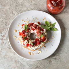 plate with bagel with cream cheese, strawberry jam and basil on the table