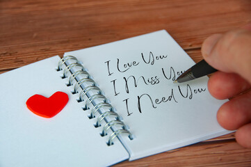 I love you text on notepad with wooden cover and pen background. Romance and relationship concept