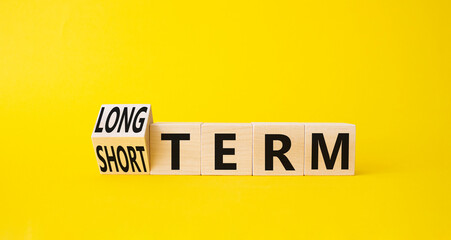 Long term vs Short Term symbol. Turned wooden cubes with words Long term and Short Term. Beautiful yellow background. Business concept. Copy space.