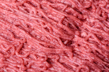 Fresh minced beef on cutting board on dark background with ingredients for cooking