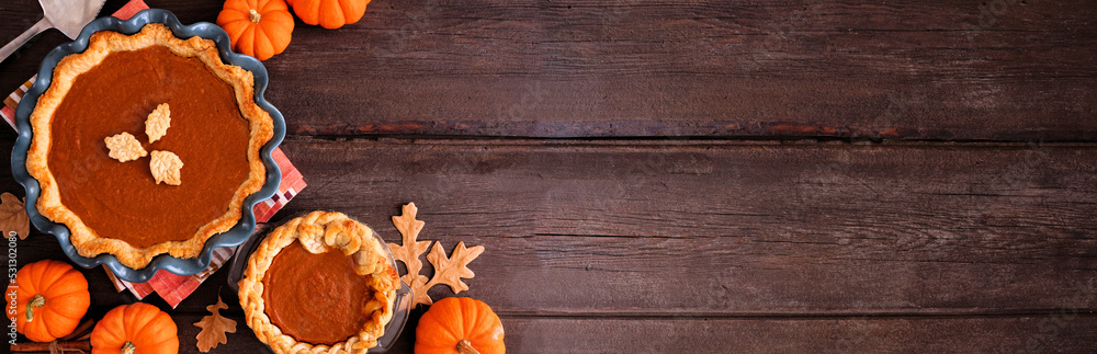 Poster homemade autumn pumpkin pies. top down view table scene on a dark rustic wood banner background with