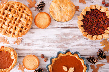 Variety of homemade fall pies. Pumpkin, apple and pecan. Top down view frame on a white wood...