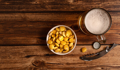 Bowl with salted lupins and glass of beer on wooden table background. Flay lay, copy space