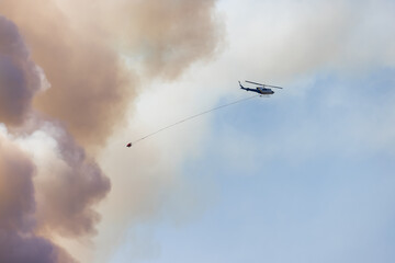Wildfire Service Helicopter flying over BC Forest Fire and Smoke on the mountain near Hope during a hot sunny summer day. British Columbia, Canada. Natural Disaster