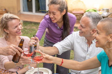 Friends toasting with beautiful smile around the table at house patio diner.