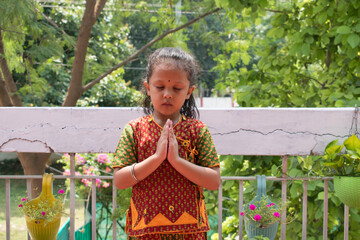 Indian girl in traditional clothes holding palms together in Namaste gesture. Smile and lookin at...