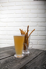 Thin sausages for beer in a beer glass. Next to it is a glass of wheat beer. Background from pine boards. Close-up.