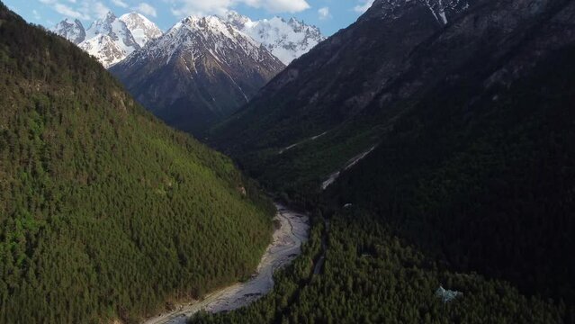 flying at high altitude over a forest and a river in a gorge in the Caucasus mountains.