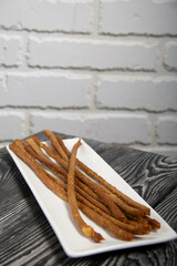 Thin sausages for beer. On a rectangular plate. Background from pine boards. Close-up.