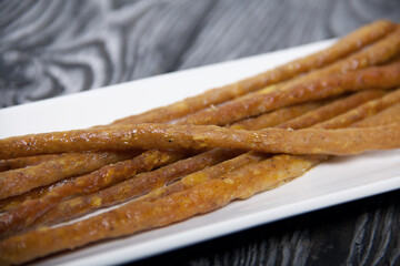 Thin sausages for beer. On a rectangular plate. Background from pine boards. Close-up.