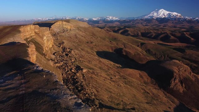 an epic flight over the abyss with a view of Mount Elbrus, along the cliff wall on the Bermamyt plateau. Elbrus is the highest peak of the Caucasus and Europe. Sunset. 