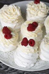 Cake Anna Pavlova, meringue and cream. Garnished with raspberries. Lying on a platter, close-up.