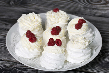 Cake Anna Pavlova, meringue and cream. Garnished with raspberries. Lying on a platter, close-up.