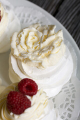 Cake Anna Pavlova, meringue and cream. Garnished with raspberries. Lying on a platter, close-up.