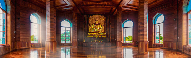 Teak hall and golden Buddha statues inside the temple chedi illuminated by the windows. Make you feel amazed by the beauty of the pagoda.
