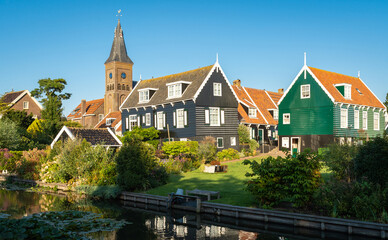 Dutch touristic village of Marken, view of the church tower and wooden houses along the canal - obrazy, fototapety, plakaty