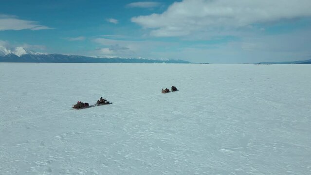 follow the train of snowmobiles in endless arctic landscape against blue sky