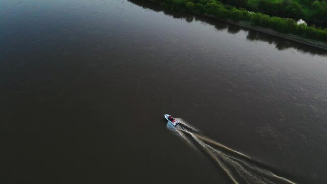 top view of floating on a river speed boat of coastal rescue service with human in orange life vests during the sunset