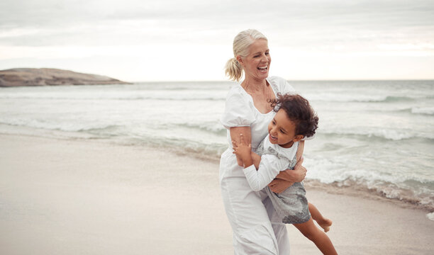 Beach, fun and grandmother playing with child for holiday, bonding and care together by the ocean. Summer, vacation and happy relationship with young foster girl and grandma embracing by the sea