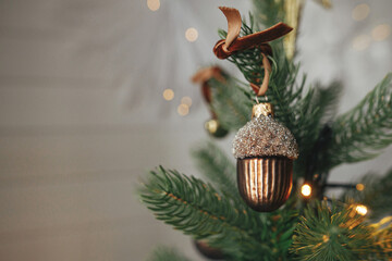 Christmas tree with vintage acorn and baubles with golden lights close up. Modern decorated...