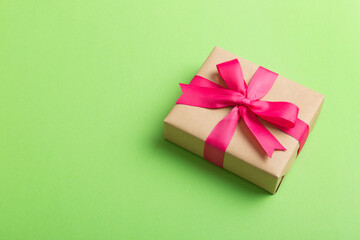 Wrapped christmas or other holiday handmade present in craft paper with colored ribbon. Present box, decoration of gift on table, top view with copy space