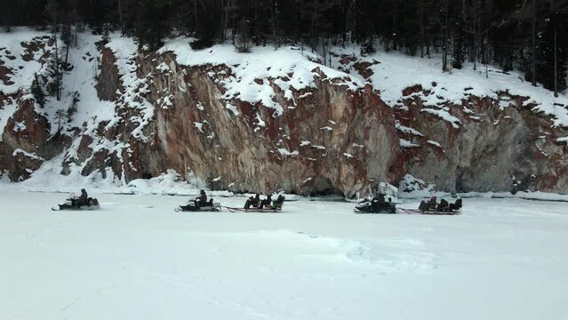 expedition on the few snowmobiles past the rocky shore on the frozen lake Baikal