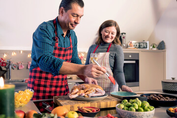 Happy man and woman cooking together traditional dinner for Christmas at home kitchen