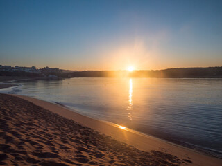 Orange sunrise at empty sand beach Praia da Franquia at Vila Nova de Milfontes with Mira river and...