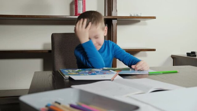 a five-year-old boy draws with a pencil